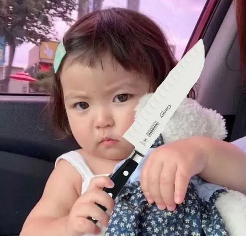 Ảnh chế em bé cầm dao mang biểu cảm căng thẳng.
